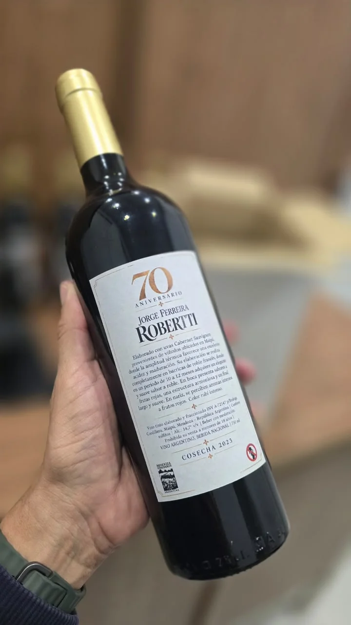 Dorso de una botella con etiqueta blanca y una dedicatoria por un aniversario de setenta años